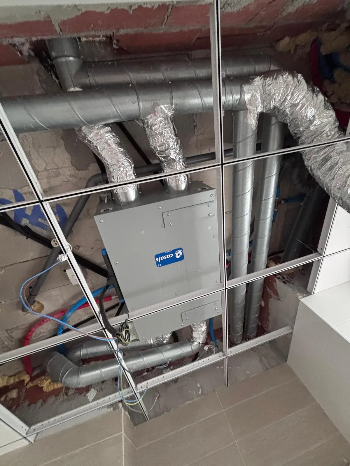 Recuperador de calor instalado en el falso techo con sus conductos de ventilación