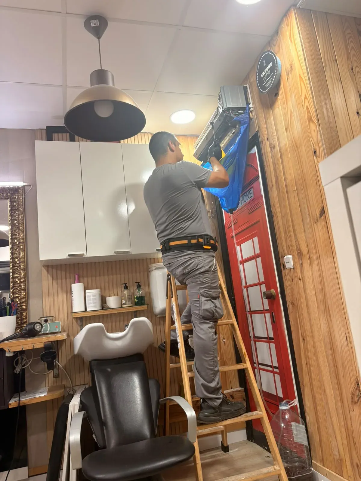 Técnico montando un split de aire acondicionado sobre una escalera