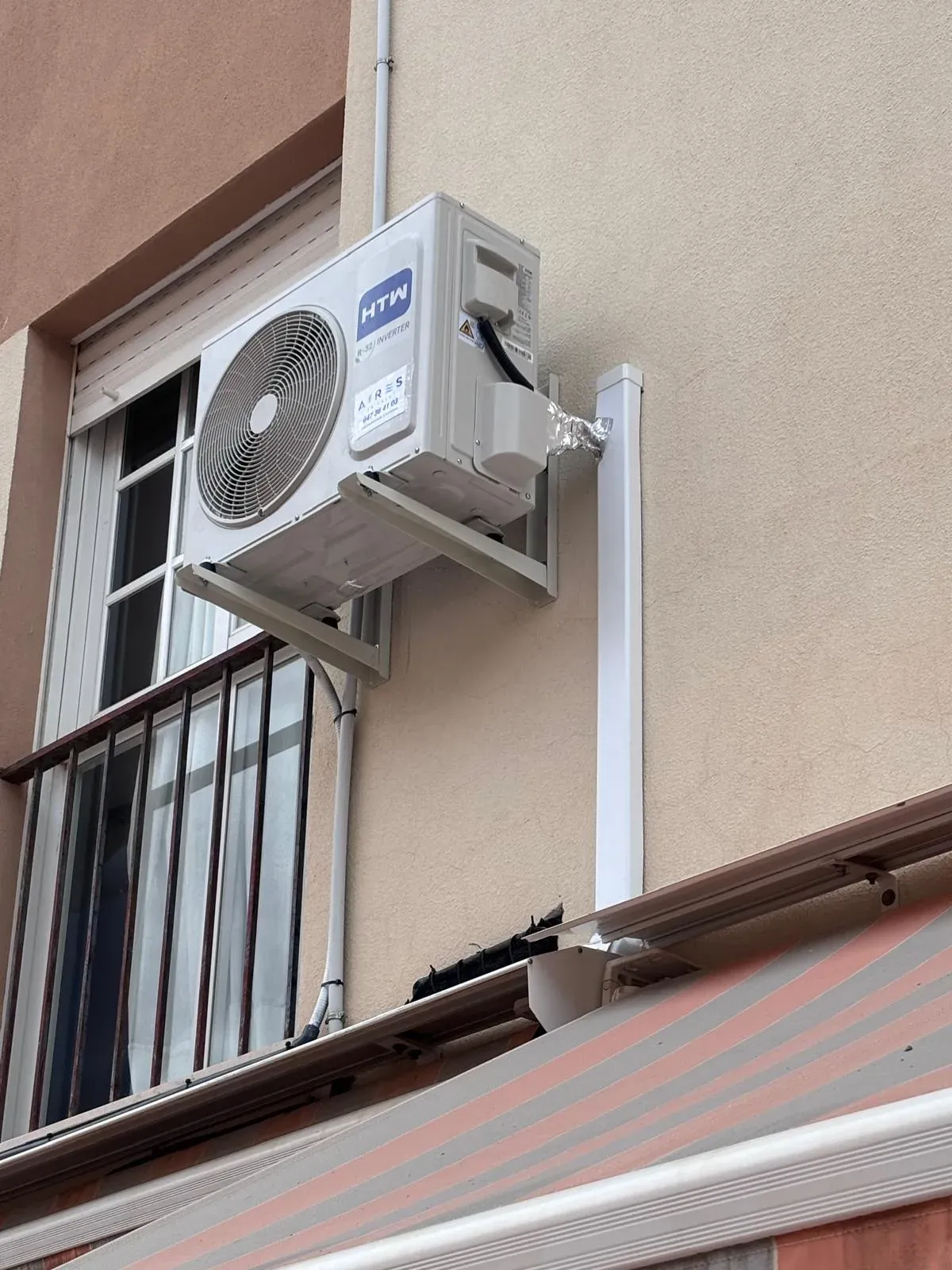 Unidad exterior de aire acondicionado instalada en la fachada de una vivienda